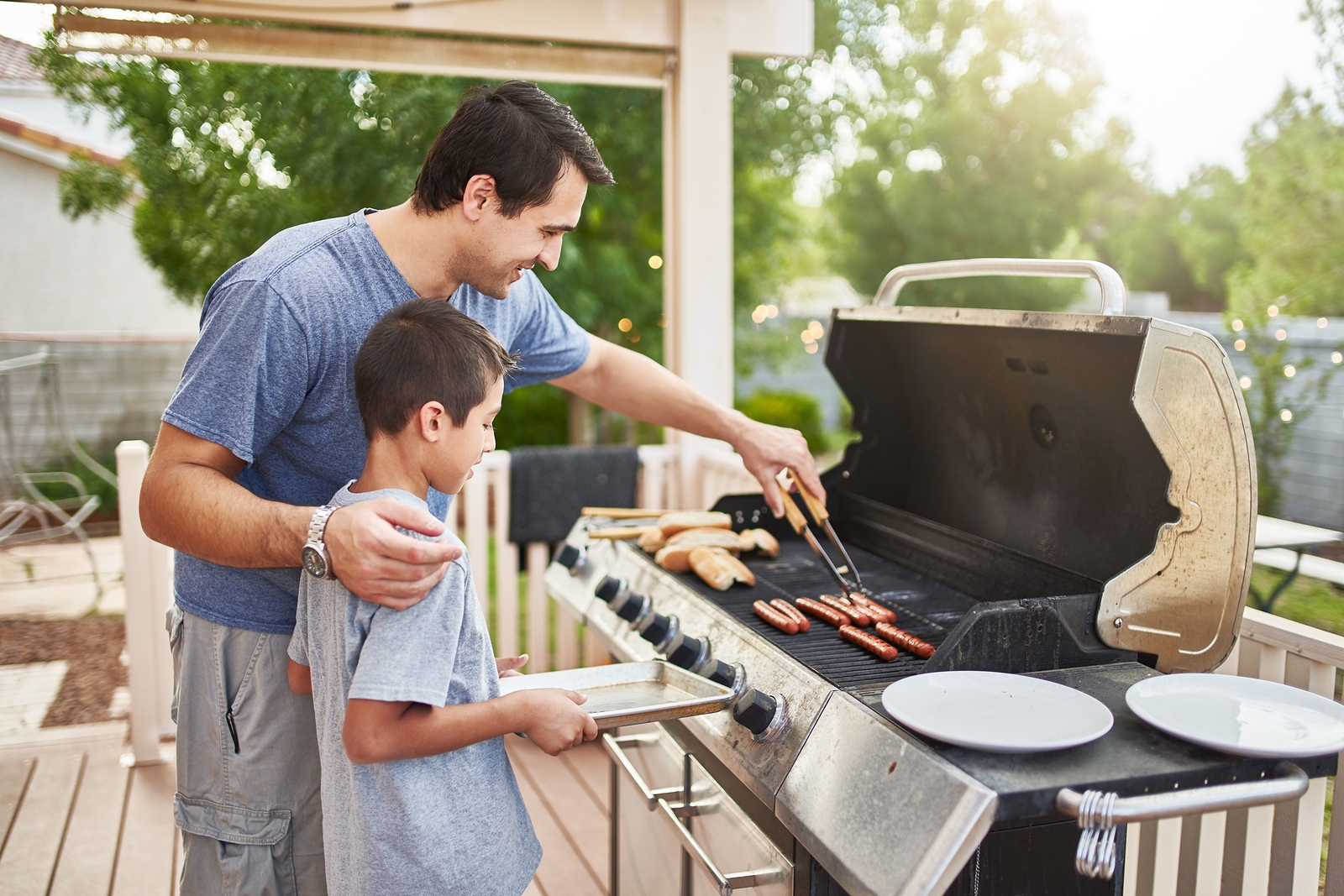 father teaching son how to grill